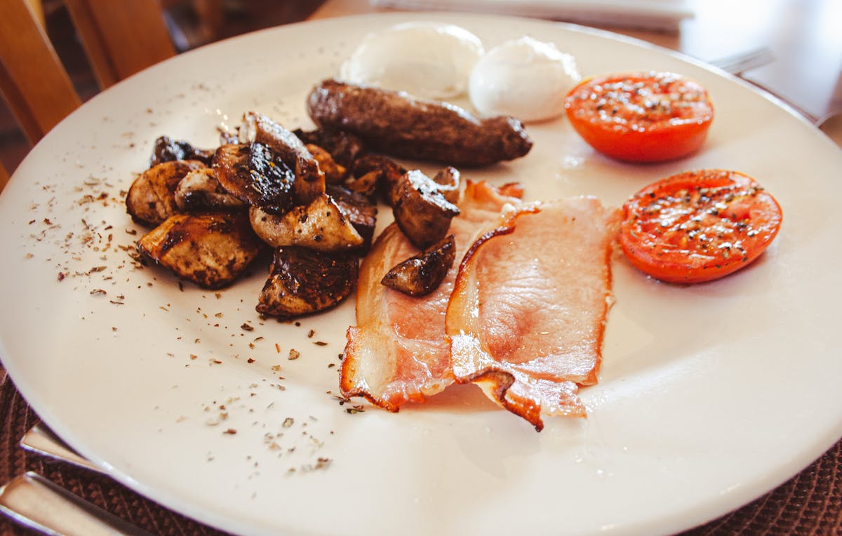 Engels ontbijt met spek, eieren en gegrilde tomaten op bord