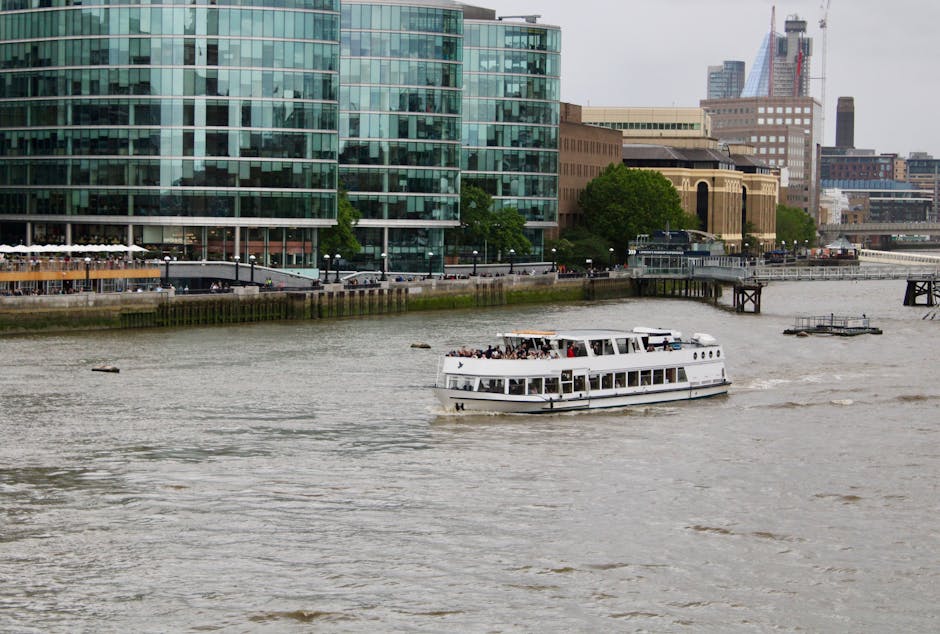 Sightseeing boat on River Thames with London city skyline.