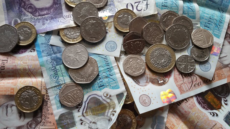 Close-up of various British pound coins and banknotes displaying Queen Elizabeth II's portrait.