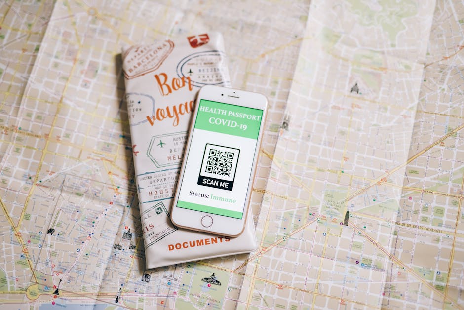Top view of a smartphone with COVID-19 health passport and travel documents on a map.