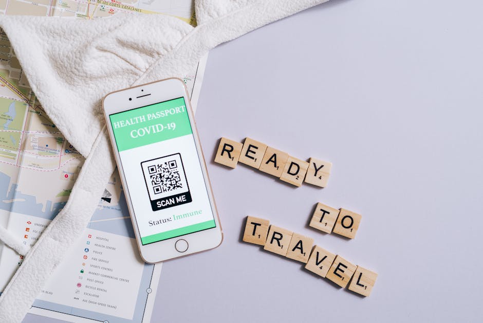 A smartphone showing a COVID-19 health passport next to Scrabble letters spelling 'Ready to Travel'.