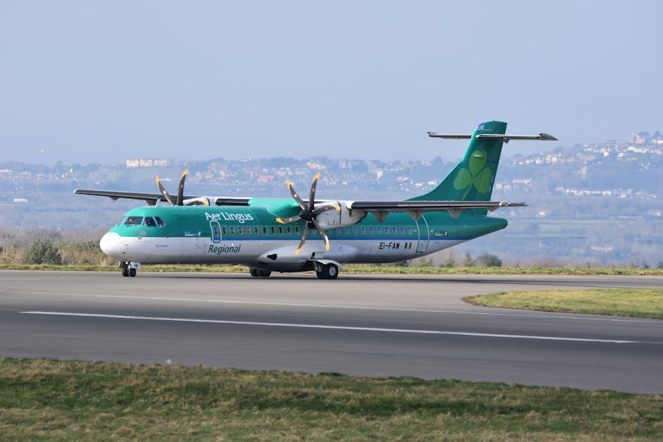 Aer Lingus Regional passenger plane taxiing on an airport runway with scenic background.