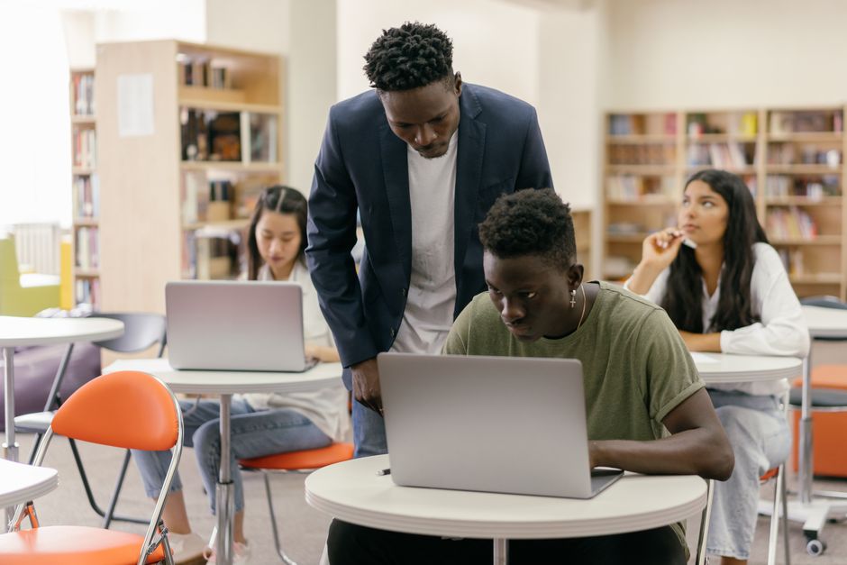 Studente bekijkt visumformulieren op een laptop in de bibliotheek