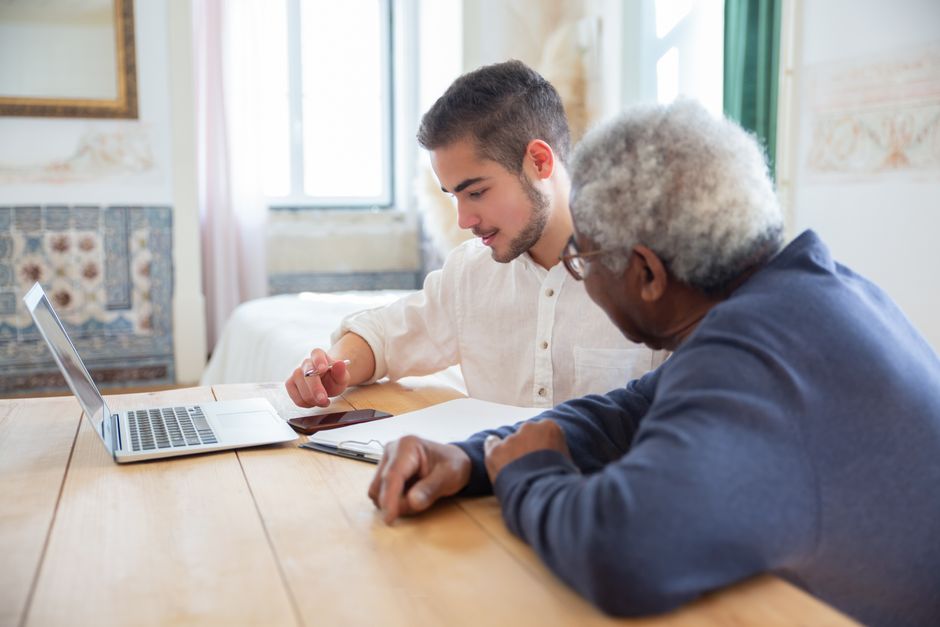 Volwassen kind helpt oudere ouders met een reisdocument achter de laptop